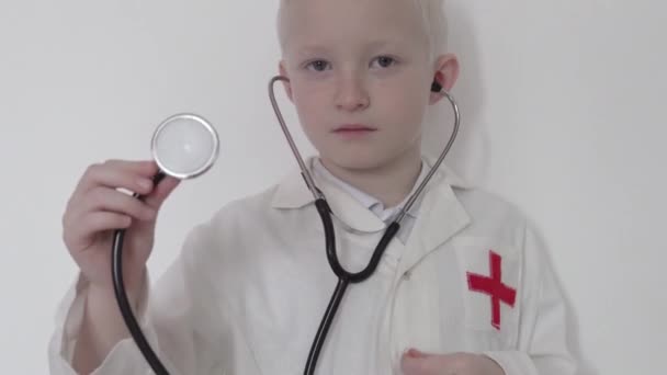 Primer plano del niño en bata de laboratorio médicos mostrando su estetoscopio contra — Vídeo de stock