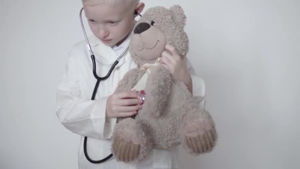 Un niño con una bata blanca interpreta a un médico — Vídeos de Stock