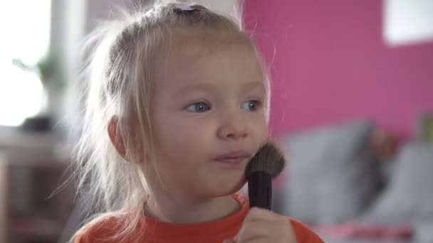 Close-up de uma menina. Bebê está pintando seu rosto com uma escova de blush — Vídeo de Stock