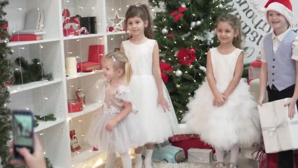 Uma mulher fotografa crianças elegantes em uma festa de Natal — Vídeo de Stock