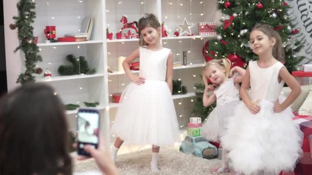 Una mujer fotografía a niños elegantes en el árbol de Navidad — Vídeo de stock