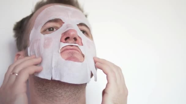Ένας άνθρωπος εφαρμόζεται μια ενυδατική μάσκα στο πρόσωπό του. — Αρχείο Βίντεο