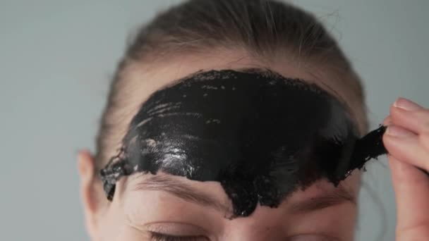 A woman removes the remains of a black film mask from her forehead — Stock Video