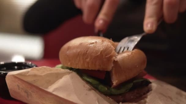 La mano femenina corta una gran hamburguesa de carne jugosa — Vídeos de Stock