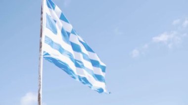 Yunanistan 'ın büyük bir bayrağı gökyüzüne beyaz bulutlarla karşı rüzgarda çırpınıyor.