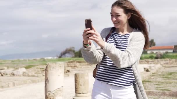 若い女性は歩きながら携帯電話で自分撮りを取る — ストック動画