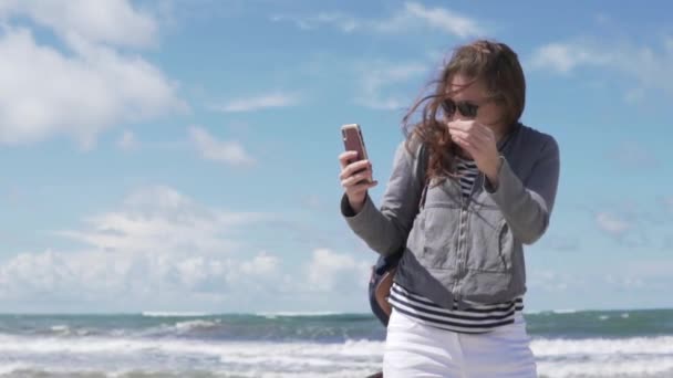 Жінка фотографує селфі по телефону на фоні моря — стокове відео
