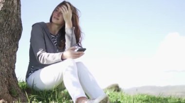 Genç bir kadın cep telefonuyla oynuyor