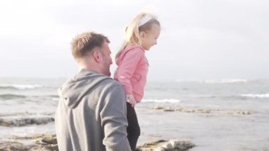 Baba küçük kızını kaldırıyor.