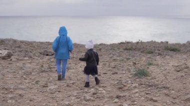 Erkek ve kız kardeş denizdeki kayalıklarda yürüyorlar.