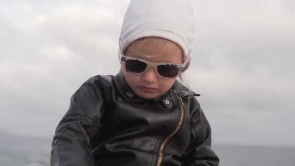 Κομψό μικρό κορίτσι σε δερμάτινο δερμάτινο μπουφάν και γυαλιά ηλίου συνομιλία — Αρχείο Βίντεο