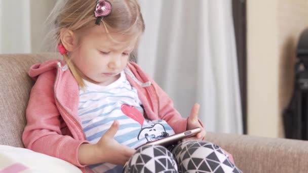 Menina olha entusiasticamente para um telefone móvel — Vídeo de Stock