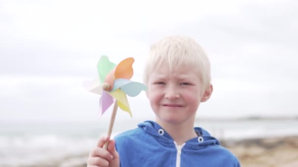 Jongen blond houdt een windmolen speelgoed — Stockvideo