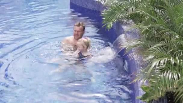 お父さんはプールで彼の小さな娘に体操をします — ストック動画