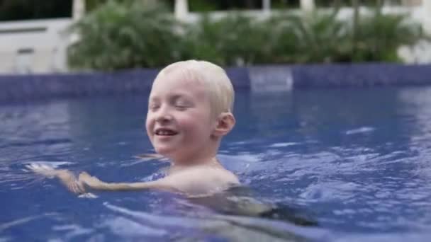Bonito menino loiro nada na piscina exterior . — Vídeo de Stock