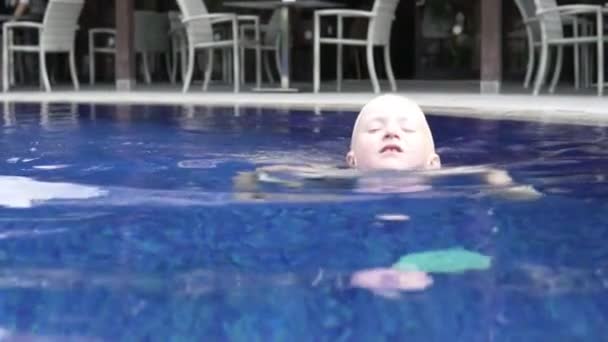 ハンサムな男の子ブロンドは、屋外プールで泳ぐ. — ストック動画