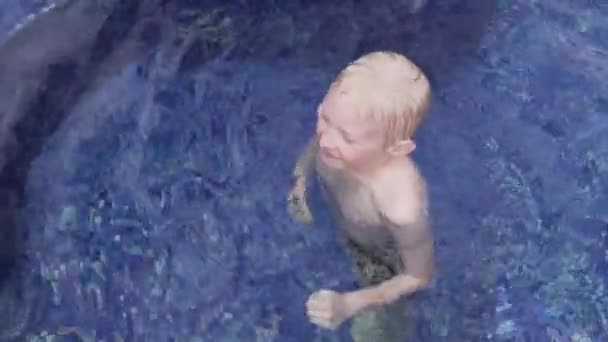 Pohledný chlapec, plavovlasý ve venkovním bazénu — Stock video