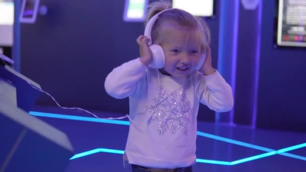 Ein schönes kleines Mädchen hört Musik in Sammlungen — Stockvideo