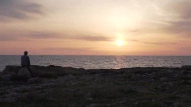 Yaşlı bir adam denizde güzel bir gün batımı nı izliyor.