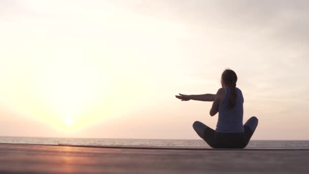 Mujer haciendo yoga y observando la puesta de sol en el mar . — Vídeos de Stock