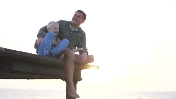 Pappa med sin son tittar på solnedgången i havet — Stockvideo