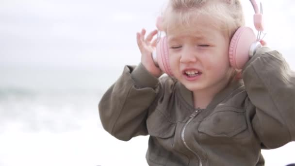 Linda niña escuchando música en los auriculares en la playa — Vídeo de stock