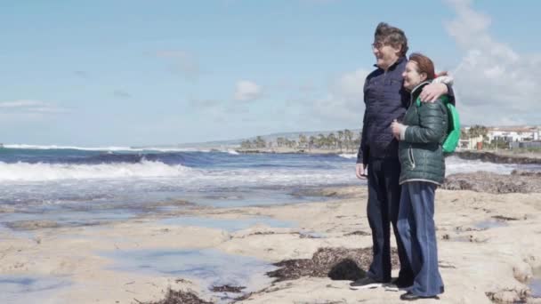Starší muž a žena se objímají na pláži — Stock video