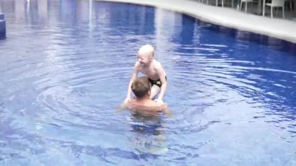 Мальчик с папой играют в бассейне на улице — стоковое видео