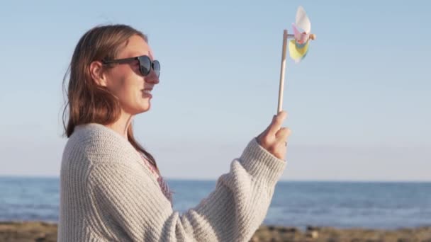 Mooie vrouw in zonnebril op zomer vakantie spelen met speelgoed windmolen — Stockvideo