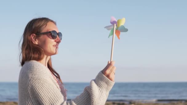 Όμορφη γυναίκα σε γυαλιά ηλίου στις καλοκαιρινές διακοπές παίζοντας με τον ανεμόμυλο παιχνίδι — Αρχείο Βίντεο