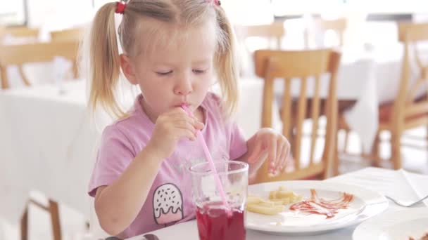 Hermosa niña comiendo papas fritas con ketchup en un café — Vídeos de Stock