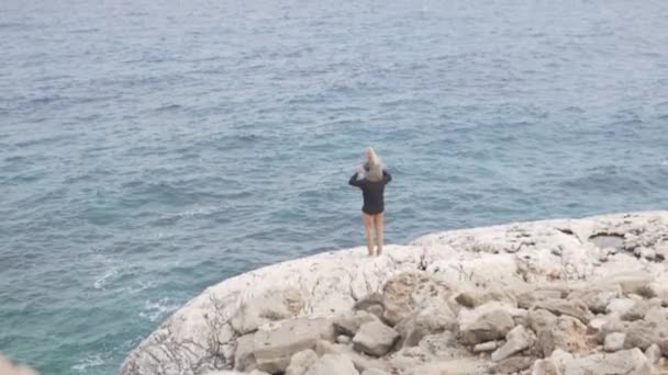 Мужчина с маленькой дочерью спустился в высокую скалу к морю — стоковое видео