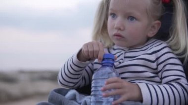 Sarışın Küçük kız yaz parkında plastik bir şişeden su içme