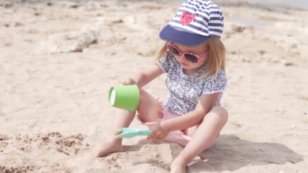 Un bambino biondo sta giocando con la sabbia sulla spiaggia — Video Stock