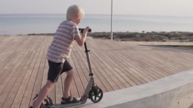 Deniz inde parkta scooter kullanan bir çocuk..