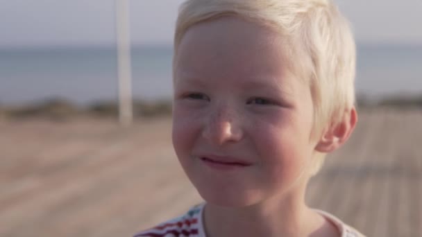 Közeli arca egy gyönyörű szőke fiú. a baba aranyos mosolygós — Stock videók