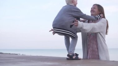 Oğlu deniz tarafından sahilde anne kucaklar.