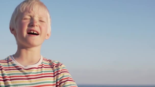 Mavi gökyüzüne karşı sarışın bir çocuğun yakın çekim — Stok video