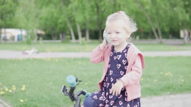 Маленькая блондинка разговаривает по игрушечному телефону — стоковое видео