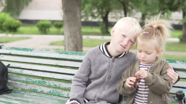 Äldre bror kramar försiktigt yngre syster i parken — Stockvideo