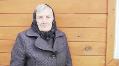 Siyah türbanlı yaşlı bir büyükanne bir evde duruyor.