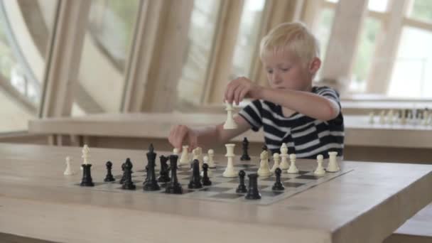 De jongen speelt schaak. Het kind maakt de verhuizing een officier — Stockvideo