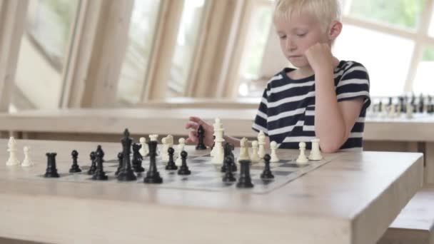 Poważny przystojny chłopiec blond gra w szachy — Wideo stockowe