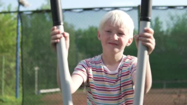 Το αγόρι πηγαίνει για αθλήματα σε ένα ελλειπτικό γυμναστή στο πάρκο το καλοκαίρι — Αρχείο Βίντεο