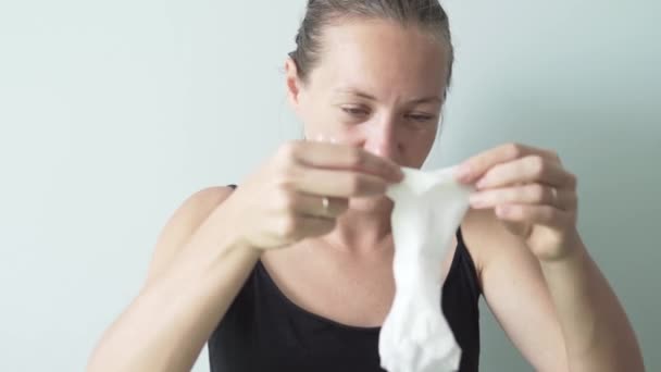 Vrouw zet op haar gezicht weefsel masker — Stockvideo