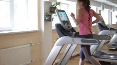 young woman running on the treadmill simulator in the gym