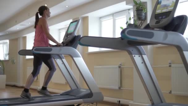 Kobieta biegnie na bieżni symulatora w klubie sportowym — Wideo stockowe