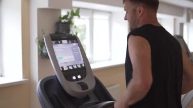 spor salonunda adam bir koşu bandı üzerinde çalışır.