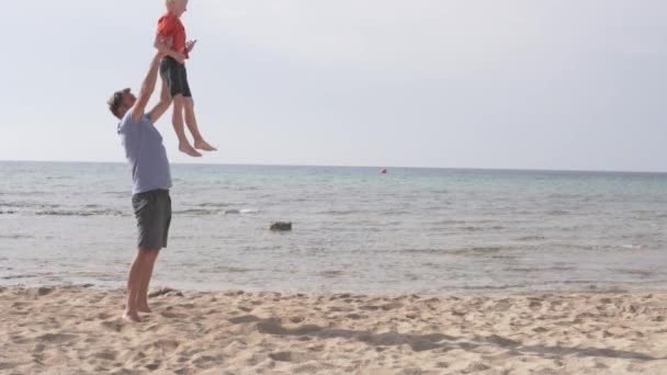 父亲和儿子在日落时在海滩上玩乐, — 图库视频影像
