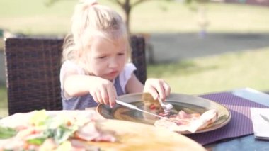 Sokakta bir kafede pizza yiyen sevimli küçük kız